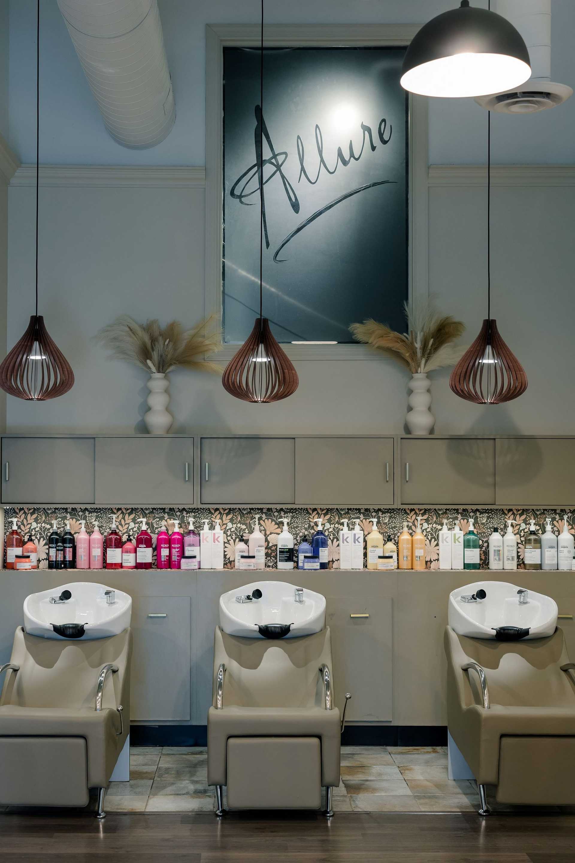 Modern hair salon with three wash stations, stylish lighting, and shelves of hair products.