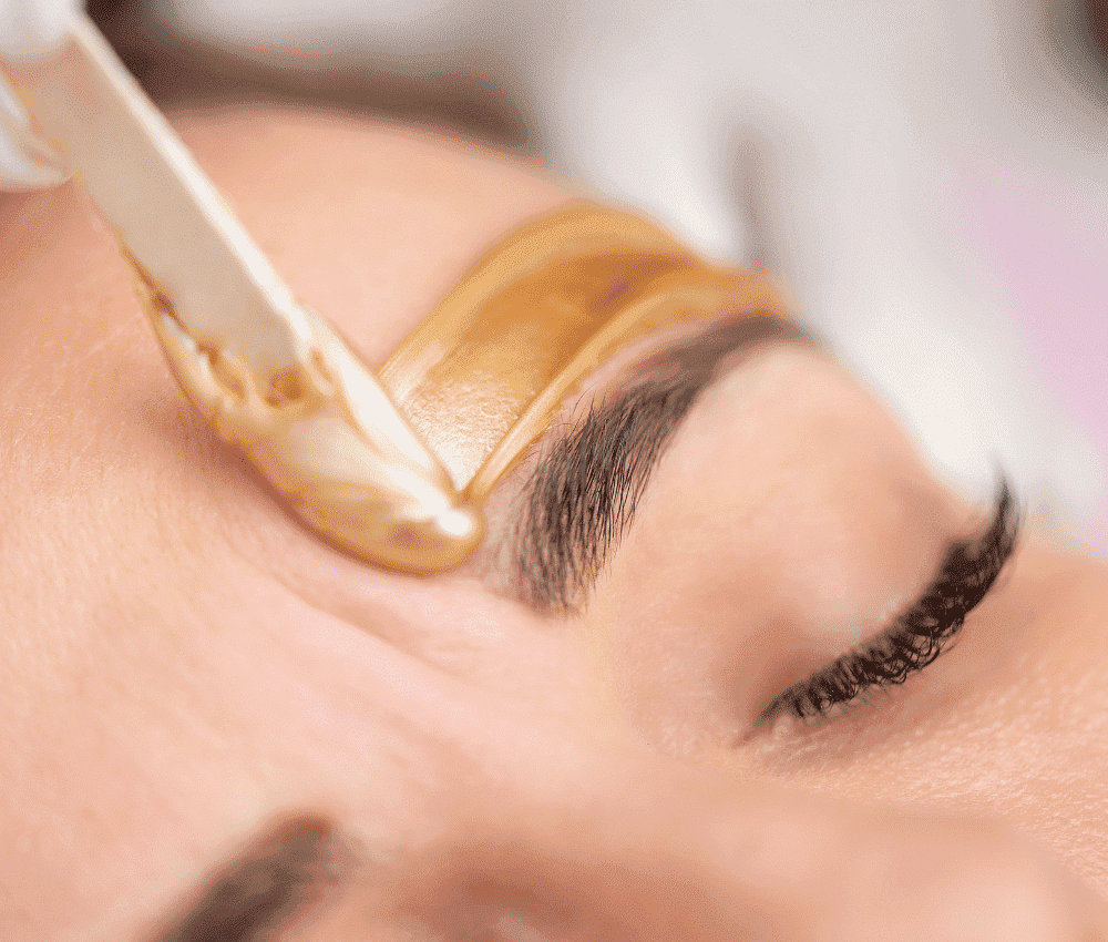 Eyebrows being shaped with warm wax for grooming and precision.