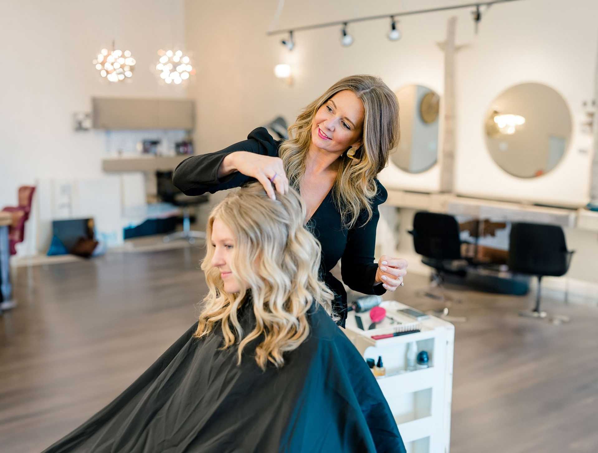 Stylist curling a woman's hair in a modern salon.