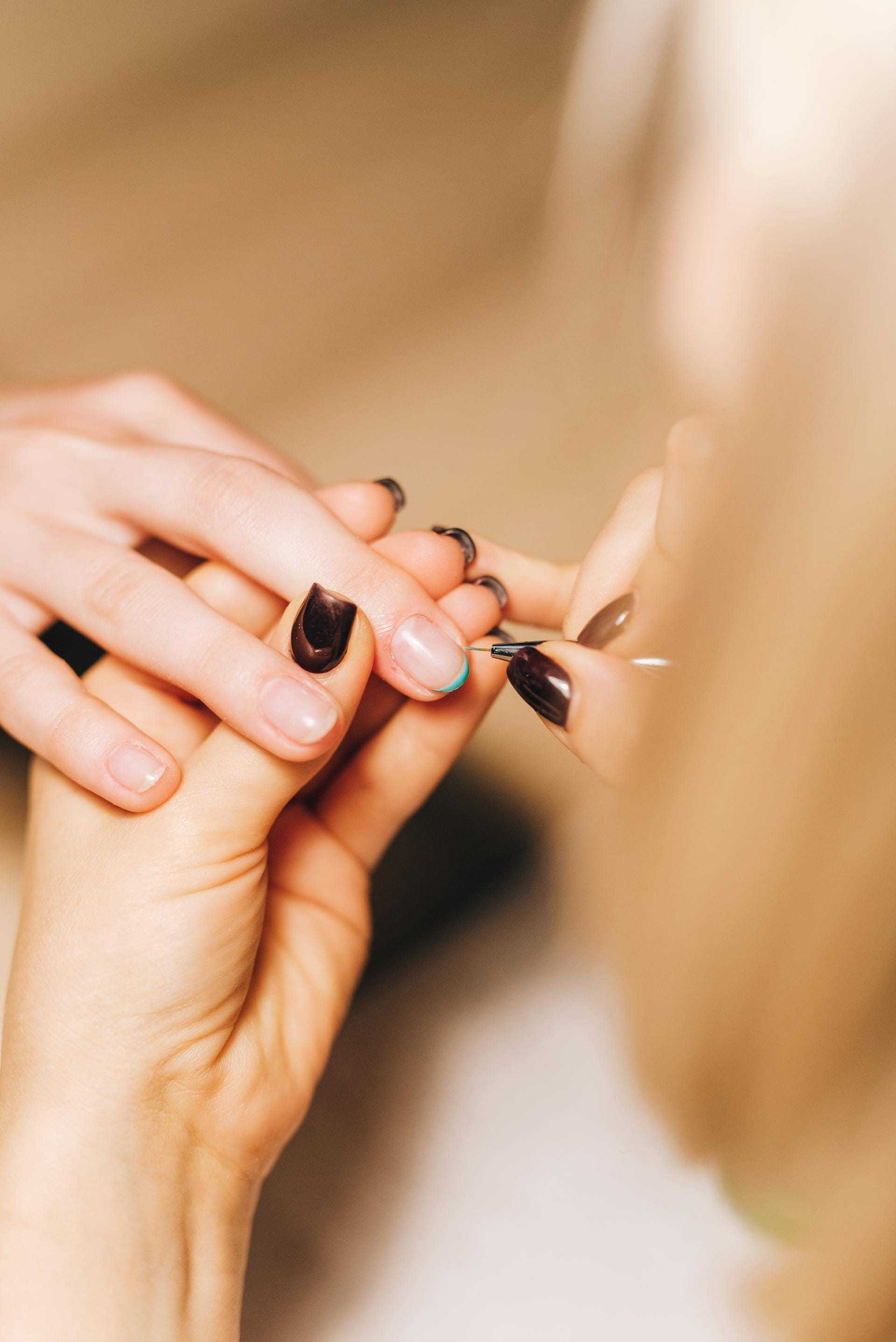 Nail technician applying polish to a client's fingernail.