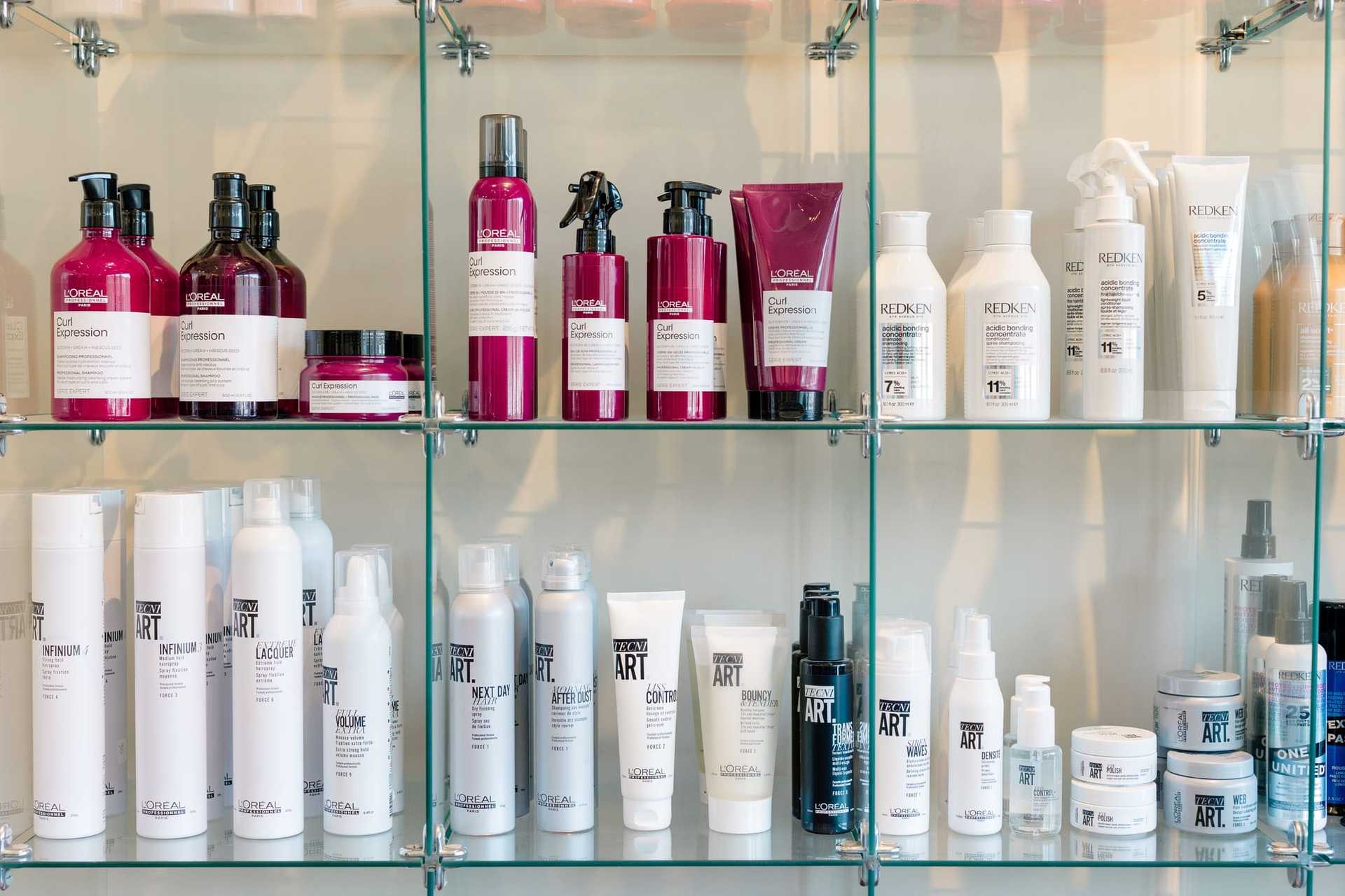 Hair care products neatly arranged on glass shelves in a salon display.