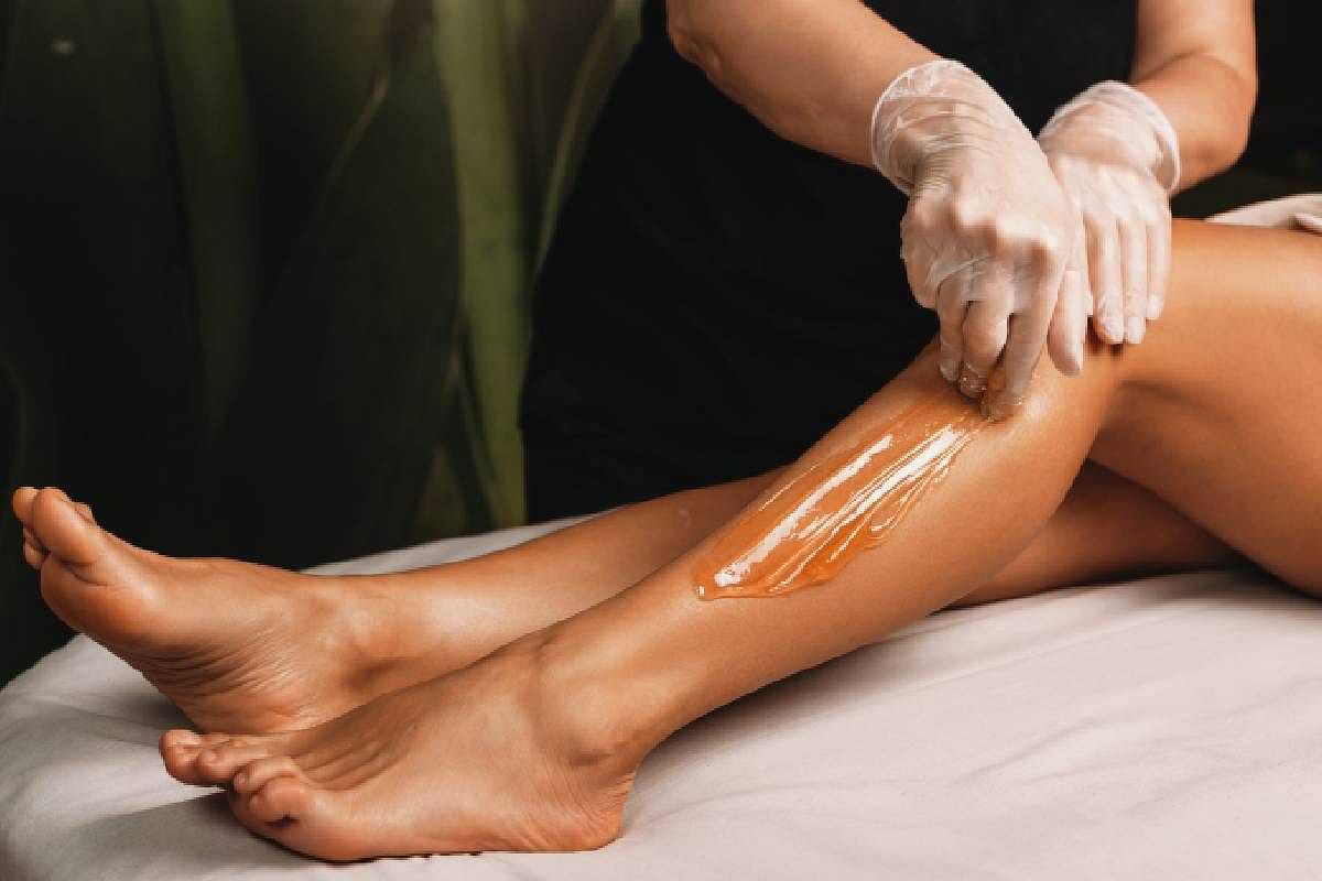 Person applying wax to a woman's leg during a waxing treatment.