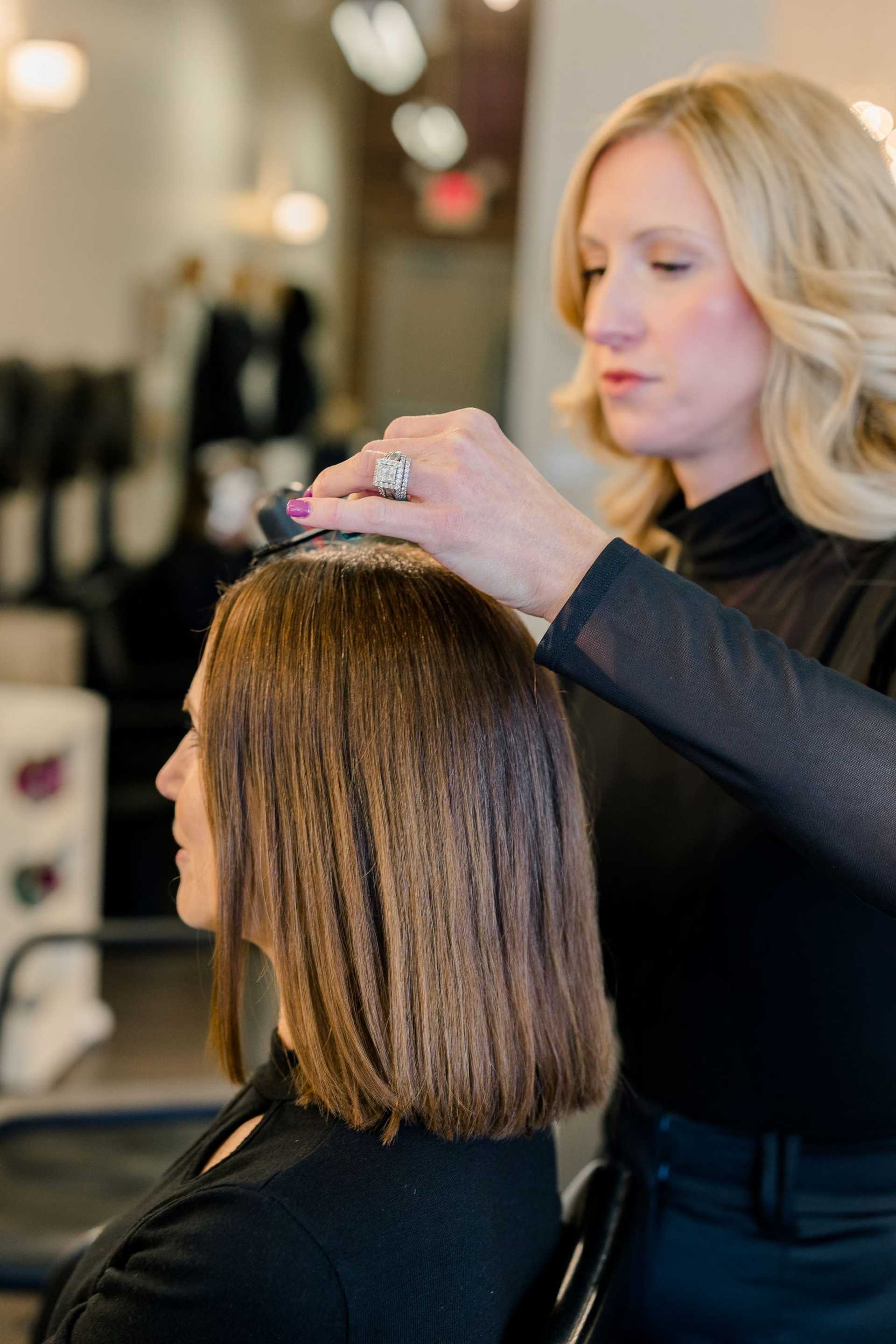 Hairstylist trimming a woman's hair in a salon.